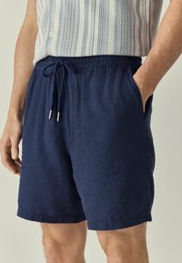Marineblå shorts med elastisk talje og snoretræk, med sidelommer og et tekstureret stof i en afslappet pasform.