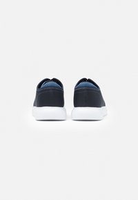 Sneakers in rete blu con una suola in gomma bianca liscia, caratterizzati da un design minimalista e due linguette posteriori per una facile calzata.