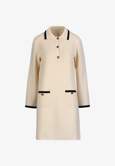 Rochie polo crem cu mâneci lungi, cu margini negre la guler, manșete, două buzunare frontale și trei nasturi pe fenta din față.