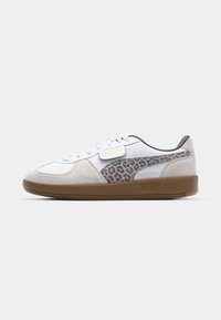 Zapatilla blanca y beige con acentos de estampado de leopardo, materiales de gamuza y cuero, suela de goma plana y cierre de cordones. Logo de PUMA visible.