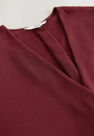 Burgundy blouse with a smooth texture, featuring a V-neck design, folded pleats at the front, and a label on the inner collar.