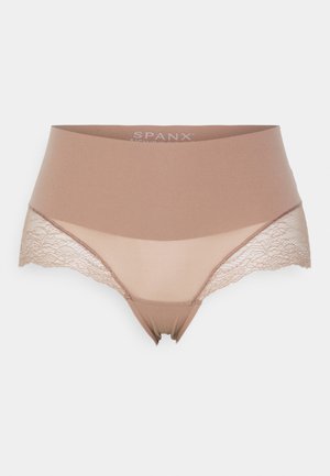 Beige ondergoed met een gladde stof en kantdetails bij de heupen. Heeft een hoog-gepauzeerd ontwerp en een subtiele glans. Gemarkeerd met "SPANX."