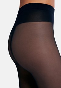 Svarta genomskinliga strumpbyxor med en slät textur, med ett brett elastiskt midjeband och en åtsittande bendesign som framhäver den transparenta finishen.