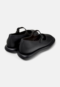 Scarpe di pelle nera con punte tonde e dettagli ritagliati, dotate di una suola spessa e imbottita per comfort e supporto.