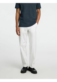 Witte broek met een rechte pijp en een minimalistisch ontwerp. Gecombineerd met een donker gestreepte shirt en zwarte schoenen. Soepele stoftextuur.