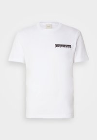T-shirt blanc manches courtes avec col rond et petit logo noir Calvin Klein New York sur le côté gauche de la poitrine.