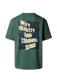 Camiseta de algodón verde con un estampado gráfico en la parte posterior que dice "DESAFÍA LA GRAVEDAD Y EL SENTIDO COMÚN", elementos gráficos mixtos y mangas cortas.