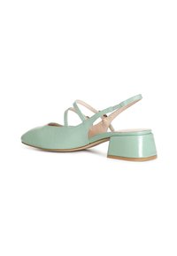Vaaleanvihreät nahkaiset matalat blokkikorkoiset slingback-kengät, joissa on ristikkäiset nilkkahihnat ja vaaleanbeige pohja valkoisella taustalla.