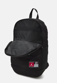 Zaino nero con superficie testurizzata, dotato di una tasca frontale, chiusura a zip e una patch con il logo "23". Fodera interna liscia.