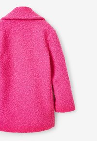 Manteau rose pelucheux avec une surface texturée, col à revers et manches longues. Il présente une coupe ample, un intérieur lisse et aucune fermeture visible.
