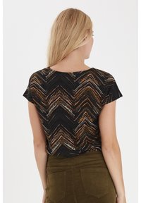 Černý top s krátkým rukávem, který má cik-cak vzor v odstínech oranžové a růžové. Měkký materiál s volným střihem a kulatým výstřihem.