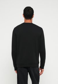 Čierna mikina s dlhými rukávmi a okrúhlym výstrihom, s rebrovaným lemom a manžetami, vyrobená z hladkej, textúrovanej tkaniny.