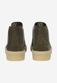 Par de zapatos en ante verde oliva con parte trasera texturizada y suela de goma beige. Presenta un ojal metálico y una lengüeta con bucle en el talón.