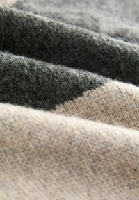 Textured knit fabric in shades of gray and beige, featuring subtle variations and patterns, highlighting a soft feel and layered design.