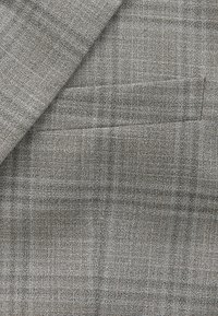 Tessuto pied-de-poule grigio, con una texture a sottile motivo a quadri. Caratterizzato da un bordo rifinito con cura e un design con una singola tasca.