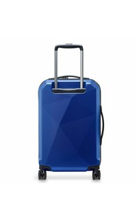 Valigia rigida blu con un design geometrico, manico estensibile, manico superiore per il trasporto e quattro ruote per la mobilità.