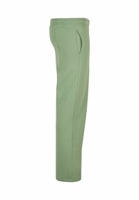 Lichtgroene joggingsbroek gemaakt van zacht materiaal, met zijzakken en een taps toelopende snit met een geribbelde tailleband bovenaan.
