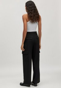 Zwarte cargo-broek met een relaxed fit, zijzakken en een soepele textuur. Gepyld met een eenvoudige grijze tanktop.