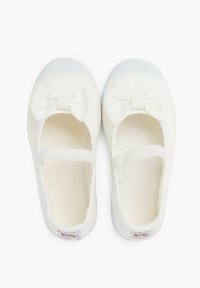 Bailarinas de tela blanca con un detalle de lazo en la parte frontal, correas elásticas y suelas de goma texturizadas. Acabado suave, diseño sencillo.