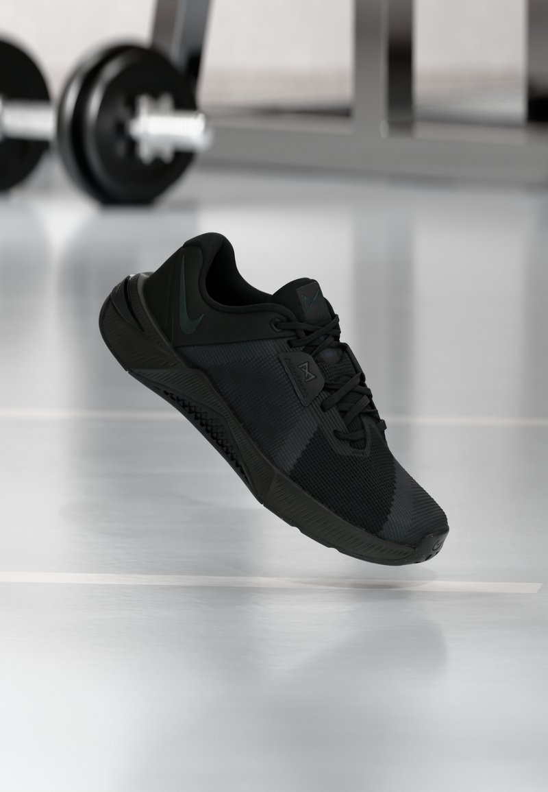 Pantof sport negru cu partea superioară din plasă texturată, sistem de șireturi și călcâi modelat. Dispune de o talpă exterioară din cauciuc negru și accente de logo contrastante verzi.