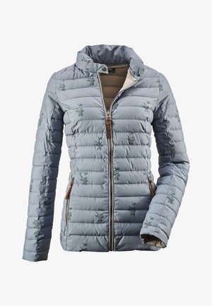 Giacca trapuntata di un blu chiaro con delicati motivi floreali, chiusura frontale con zip, colletto alto con bottoni a pressione e tasche laterali con zip, parzialmente aperta.