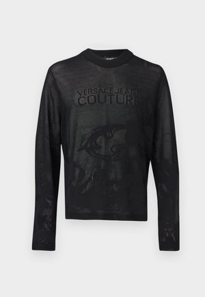 Schwarzer, langärmliger Mesh-Pullover mit "Versace Jeans Couture"-Schriftzug und dezentem Barockmuster, das durch den Stoff sichtbar ist.