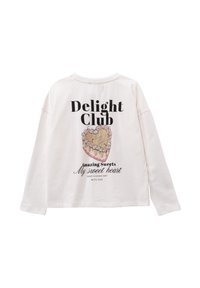 Camisa blanca de manga larga con un gran estampado gráfico de un postre y el texto "Delight Club" con acentos coloridos en la parte trasera.