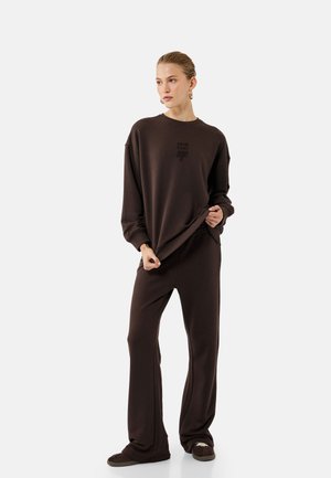 Bruine katoen sweatshirt met een ronde hals en een subtiel logo. Losse pasvorm gecombineerd met bijpassende bruine sweatpants, voorzien van een recht model.
