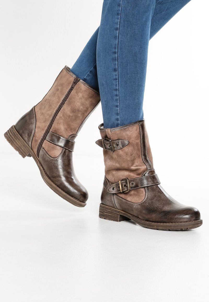 Bruna ankelstövlar med en blandad materialdesign, slät tå, strukturerade sidor, en dekorativ spänne och en låg staplad klack.