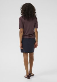 Kortærmet, maroon striktop parret med en marineblå nederdel. Brune hæle med en transparent detalje. Enkel, tætsiddende design.