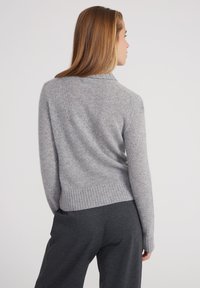 Pull en mélange de laine gris avec un ourlet et des poignets côtelés, doté d'un col classique et d'une finition douce et texturée.