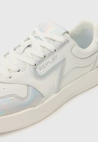 White leather sneaker featuring a shimmering iridescent accent, round toe, contrasting stitching, and a cushioned interior with laces.