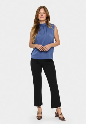 Haut sans manches bleu avec un col froncé, assorti à un pantalon noir slim-fit et des talons imprimés animaliers. Tissu lisse avec une coupe décontractée.