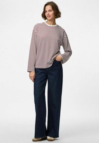 Lange mouw gestreepte shirt in wit en bordeauxrood met een ronde hals, gecombineerd met donkerblauwe wijde jeans en beige schoenen.