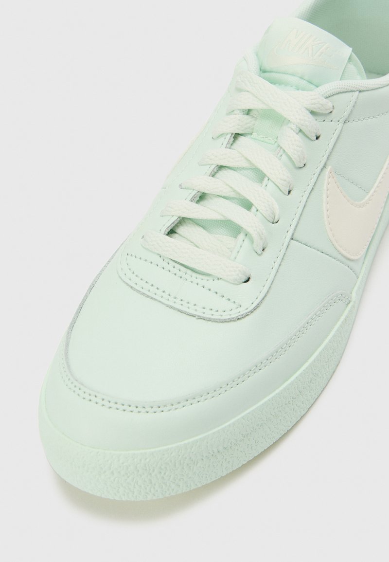 Nike Sneaker aus hellmintgrünem Leder mit tonalen Schnürsenkeln, einer strukturierten Gummisohle und einem dezenten beigen Swoosh-Logo an der Seite.