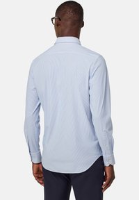 Camicia a righe blu chiaro con maniche lunghe, polsini con bottoni e colletto a punta, caratterizzata da una texture in cotone morbido e un orlo curvo.