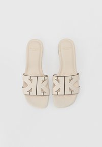 Sandales à glissière beige avec une large bride dotée d'un logo audacieux en relief. Fini lisse et mat, design ouvert au niveau des orteils et semelles plates.
