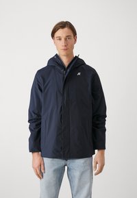 Giacca a hoodie blu navy con zip frontale, due tasche laterali e logo riflettente sul petto. Realizzata in materiale leggero e resistente all'acqua.