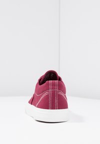 Sneaker in tela bordeaux con cuciture bianche, suola di gomma e design basso, caratterizzata da un tacco arrotondato e una texture liscia.