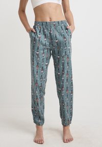Ljusblå pyjamabyxor med elastisk midja, prydda med ett mönster av nötknäppare och sidofickor; avsmalnande mudd vid anklarna.