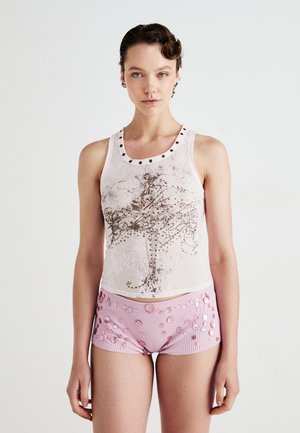 Hvit ermeløs topp med glitrende design og naglet halslinje, paret med rosa stripete shorts pyntet med paljetter og blomsterdesign.