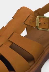 Καφέ δερμάτινο σανδάλι με πολλαπλές λουριά και χρυσή ορθογώνια αγκράφα στο πλάι για ρυθμιζόμενο κούμπωμα.