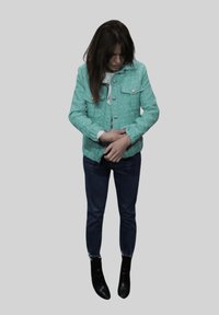 Una chaqueta de mezclilla verde menta con dos bolsillos en el pecho y botones plateados, combinada con jeans azul oscuro y botines negros.