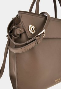 Borsa a mano in pelle marrone con design strutturato, accessori in metallo dorato e tracolla regolabile. Presenta dettagli di cucitura e logo.