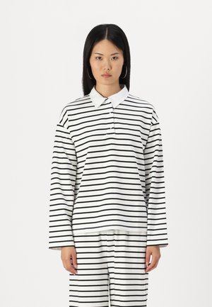 Langermet polo skjorte i hvit med svarte horisontale striper, med krage og knapplukking, laget av mykt stoff.