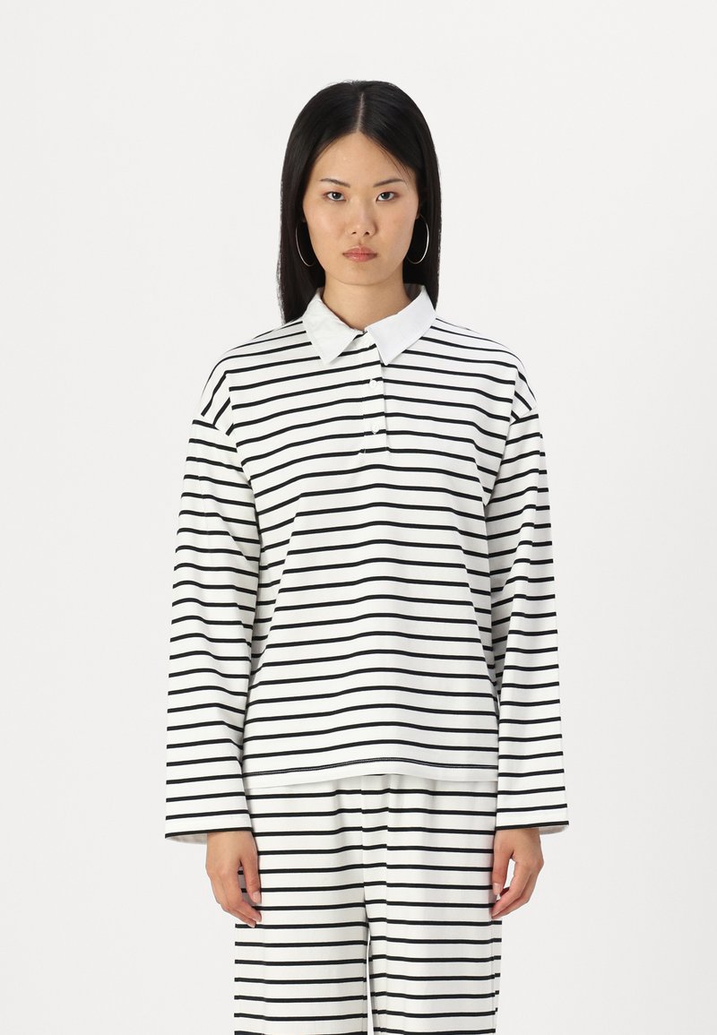 Polo à manches longues en blanc avec des rayures horizontales noires, doté d'un col et d'un rabat à boutons, fabriqué à partir d'un tissu doux.