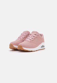 Baskets de sport roses avec une tige texturée, un design perforé, une semelle en caoutchouc et un amorti à air visible dans le talon. Fermeture à lacets flexible.