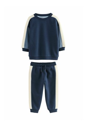Marineblå sweatshirt og sweatpants sæt med cremefarvede og lysblå farveblokke på sidepanelerne, lavet af blødt bomuldsstof med ribbede kanter.