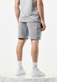 Grå cargo shorts med en avslappet passform, med sidelommer, laget av bomull og med en jevn tekstur, kombinert med hvite sneakers og sokker.