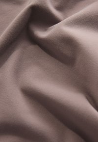 Tessuto morbido e strutturato di colore lilla tenue, con pieghe morbide e una delicata lucentezza. Adatto per diverse applicazioni nell'abbigliamento.